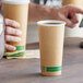 A hand holding an EcoChoice Kraft paper hot cup full of coffee.