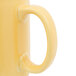 A close up of a yellow Tuxton china mug with a C-handle.