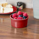 A Fiesta Scarlet China Ramekin filled with raspberries and blueberries on a table.