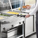 A man using a ServIt tubular fixed tray slide to serve food from a steam table.