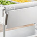 ServIt solid drop down side tray slide holding food trays on a steam table.