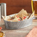 A Tablecraft stainless steel oval platter with tacos on a table.