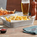 A Tablecraft stainless steel rectangular platter of french fries with a bowl of red sauce on a table.