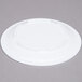 A white plastic Thunder Group Nustone melamine plate on a gray surface.