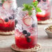 An Acopa Rustic Charm mason jar filled with red blueberry lemonade with mint and ice.