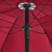 A close up of a red Lancaster Table & Seating umbrella with a black pole.
