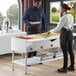 A man and woman standing next to a ServIt open well electric steam table on a hotel buffet table.