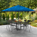A Lancaster Table & Seating cobalt blue umbrella on a patio table with chairs.