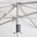 A close up of a white Lancaster Table & Seating aluminum umbrella with metal poles.