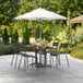 A white Lancaster Table & Seating umbrella over a table with chairs on a patio.