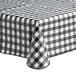 A close-up of a Choice black textured gingham vinyl table cover with flannel back on a table.