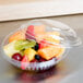 A Dart clear plastic bowl with a dome lid containing fruit.