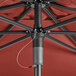 A Lancaster Table & Seating terracotta umbrella with a metal pole on a table.