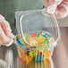 A person in gloves holding a Choice clear plastic deli container filled with gummy bears.