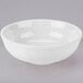A Tuxton porcelain white bowl with a white rim on a gray surface.