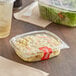 A clear plastic Choice deli container of pasta salad on a table with a white band.