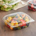 A clear Choice RPET deli container with fruit salad and a fork.