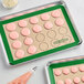 A tray of pink cookies on a Baker's Mark green silicone baking mat.