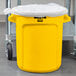 A yellow Rubbermaid BRUTE trash can with a plastic bag inside.