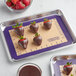 A Baker's Mark purple silicone baking mat with chocolate covered strawberries.