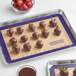 A Baker's Mark purple silicone baking mat with chocolate covered strawberries on it.