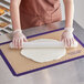 A woman rolling out dough on a purple Baker's Mark silicone baking mat.