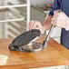 A man using a Choice cast iron tortilla press to make a tortilla.