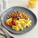 An American Metalcraft storm coupe melamine plate with scrambled eggs and orange slices.