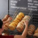 A person placing a basket of bagels into a bakery display.