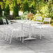 A Lancaster Table & Seating white outdoor dining set on a patio.