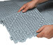 A person's hands holding a gray Cactus Mat vinyl floor tile.