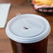 A white Cambro lid with a straw slot on a plastic cup with a straw.