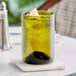 A Fortessa olive green wine tumbler filled with a green drink and ice with a lemon slice in it.