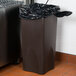 A brown rectangular trash can with a black Berry trash bag inside.