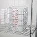 A metal rack with clear plastic Cambro food storage containers.
