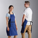 A man and woman wearing Choice royal blue restaurant aprons with black webbing accents.