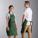 A man and woman wearing Choice hunter green aprons with black webbing accents.