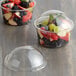 A clear plastic dome lid on a round plastic container with fruit inside.