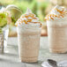 A glass of Capora Caramel Latte Frappe mix with whipped cream and caramel sauce.