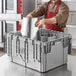 A man in an apron putting a silver Choice chafer in a grey plastic storage container.