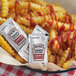 A basket of fries with Heinz Simply Ketchup packets on a table.
