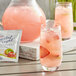 A glass of pink Crystal Light with ice and strawberries next to a bag of strawberries.