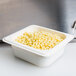 A white container of corn in a white Cambro food pan on a counter.