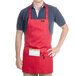 A man wearing a red Chef Revival apron with a pocket.