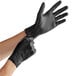 A pair of hands wearing black Noble NexGen disposable gloves.