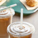 A plastic cup with a lid and two EcoChoice wrapped straws on a table with two coffee cups.