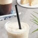 A cup of coffee with a black EcoChoice giant compostable straw.