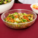 A clear Cambro round ribbed bowl filled with vegetables next to a bowl of salad.