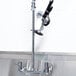 A chrome Equip by T&S wall mounted pre-rinse faucet with black handles.