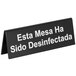 A black Tablecraft sign with white text that says "Esta mesa ha sido destinativa" in both Spanish and English.